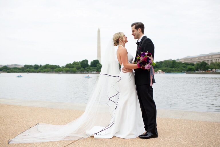 Bride and groom posing infront of water with flower bouquet