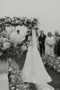 Classic elegant outdoor wedding arch, black and white photo, bride walking down the aisle