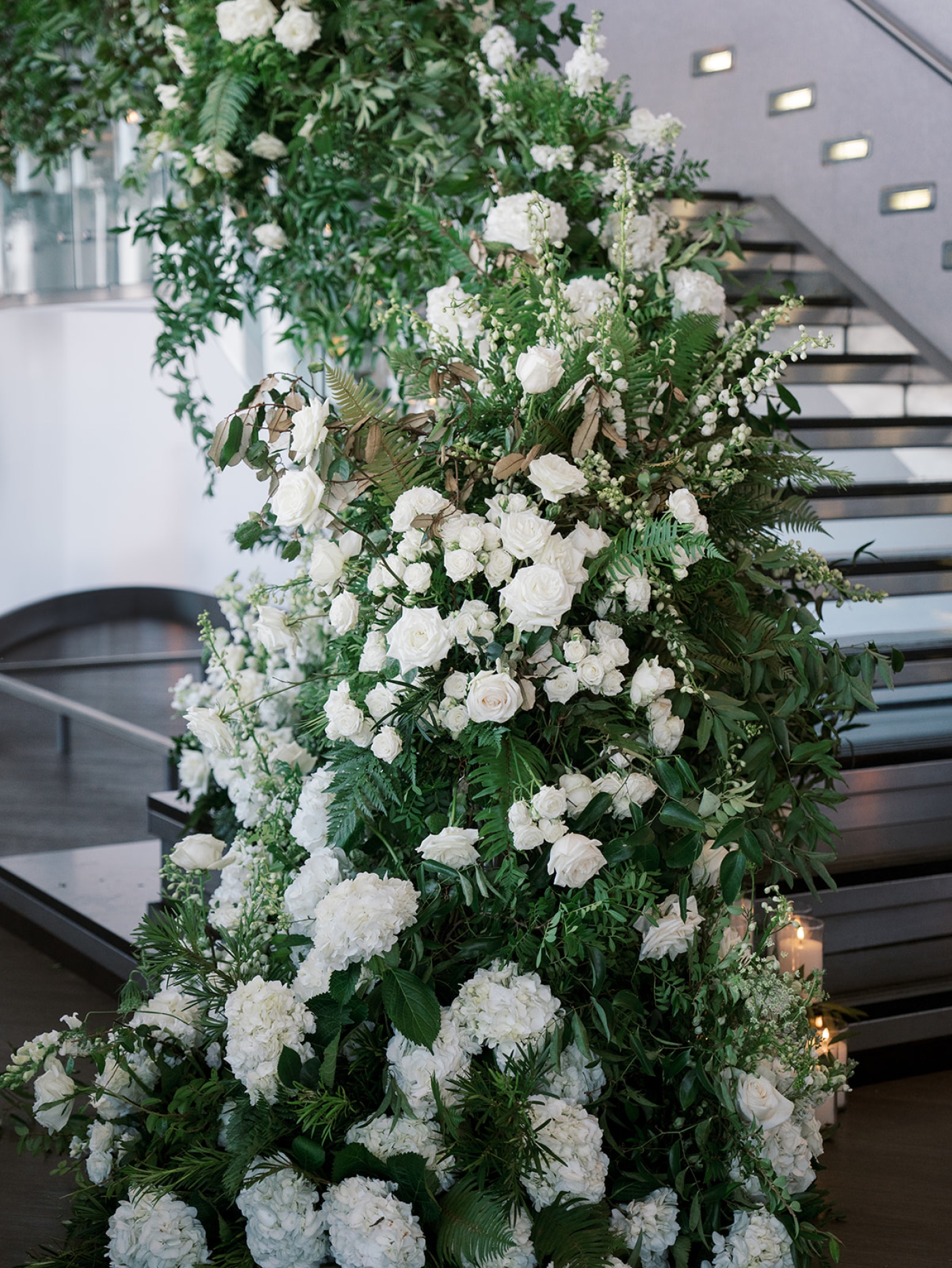 A long staircase covered in greenery and white flowers