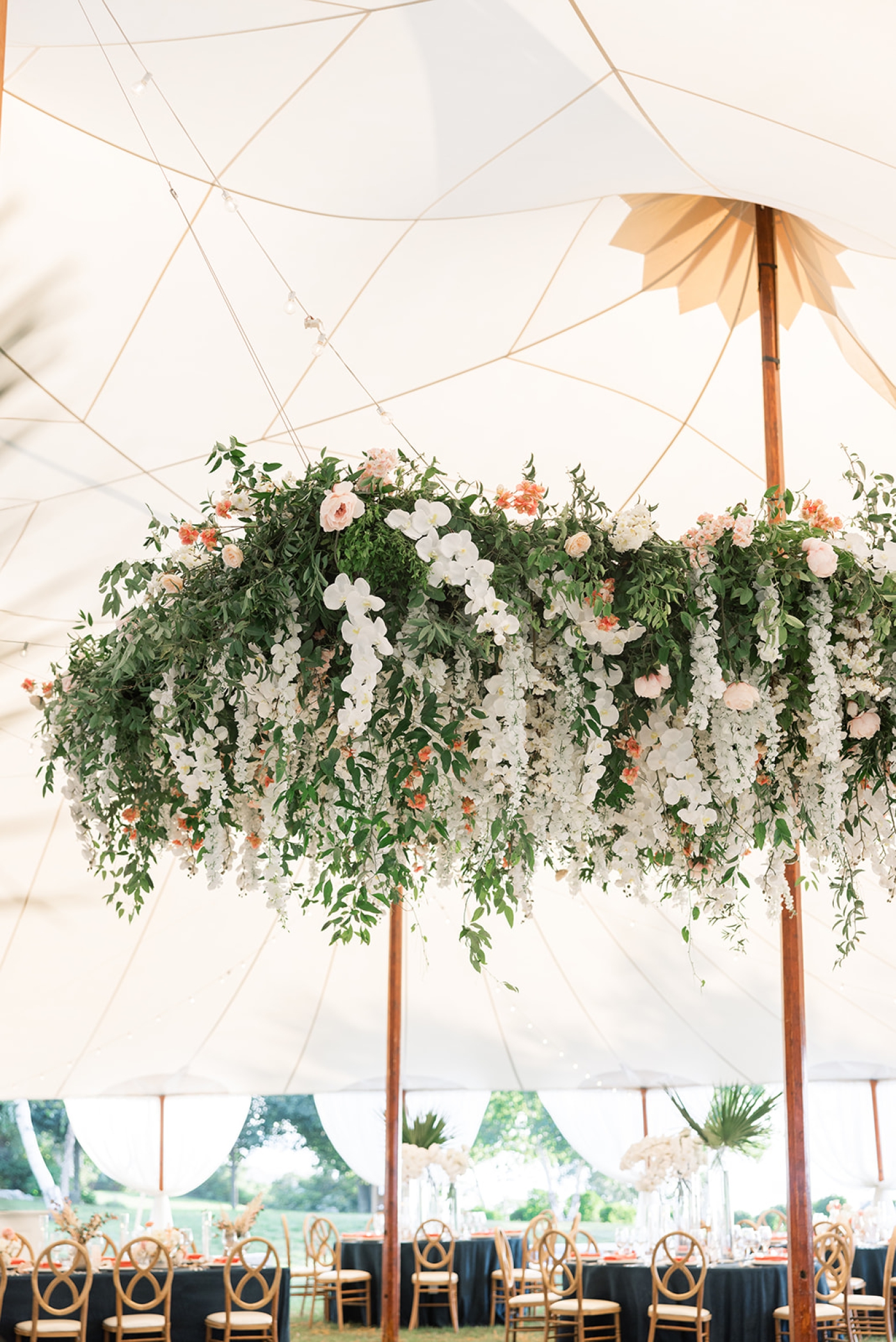 A large hanging floral installation in a tented wedding reception