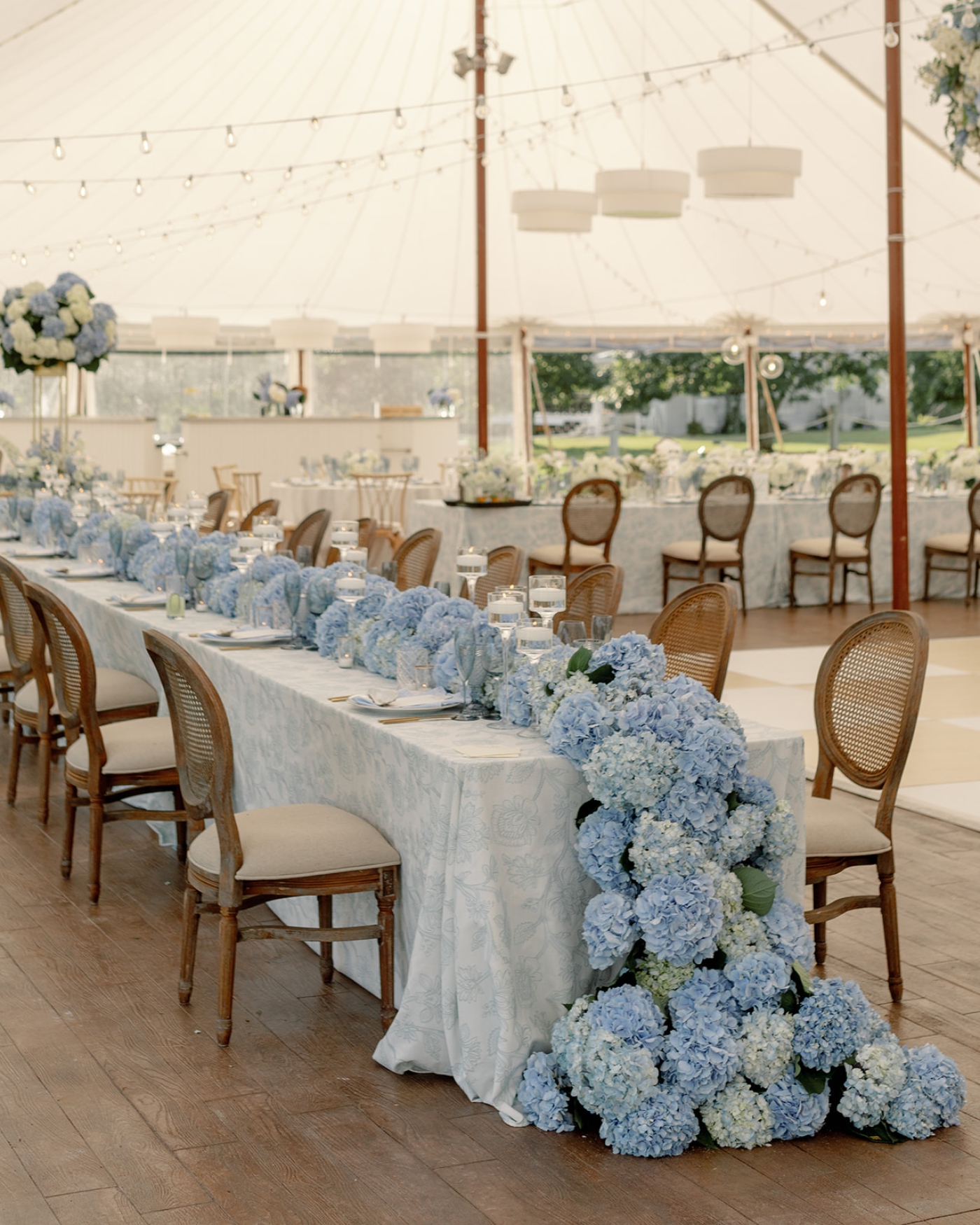A long table covered in blue and white hydrangeas at a wedding reception at French's Point