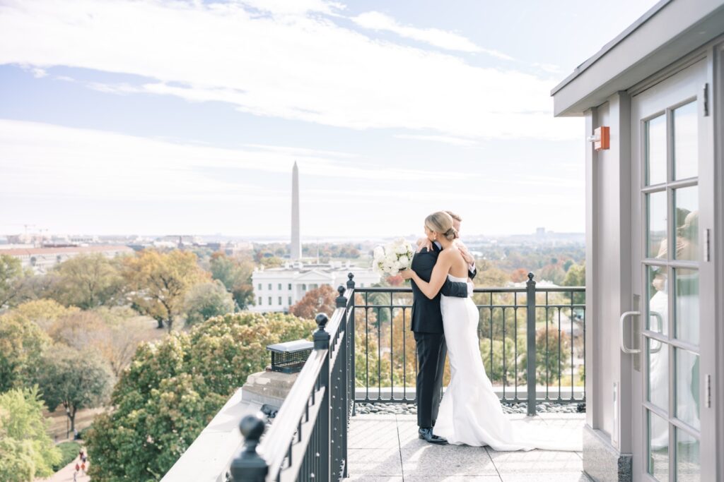 A bride and groom share a first look on the balcony of the Hay-Adams Hotel with the Washington Monument in the background