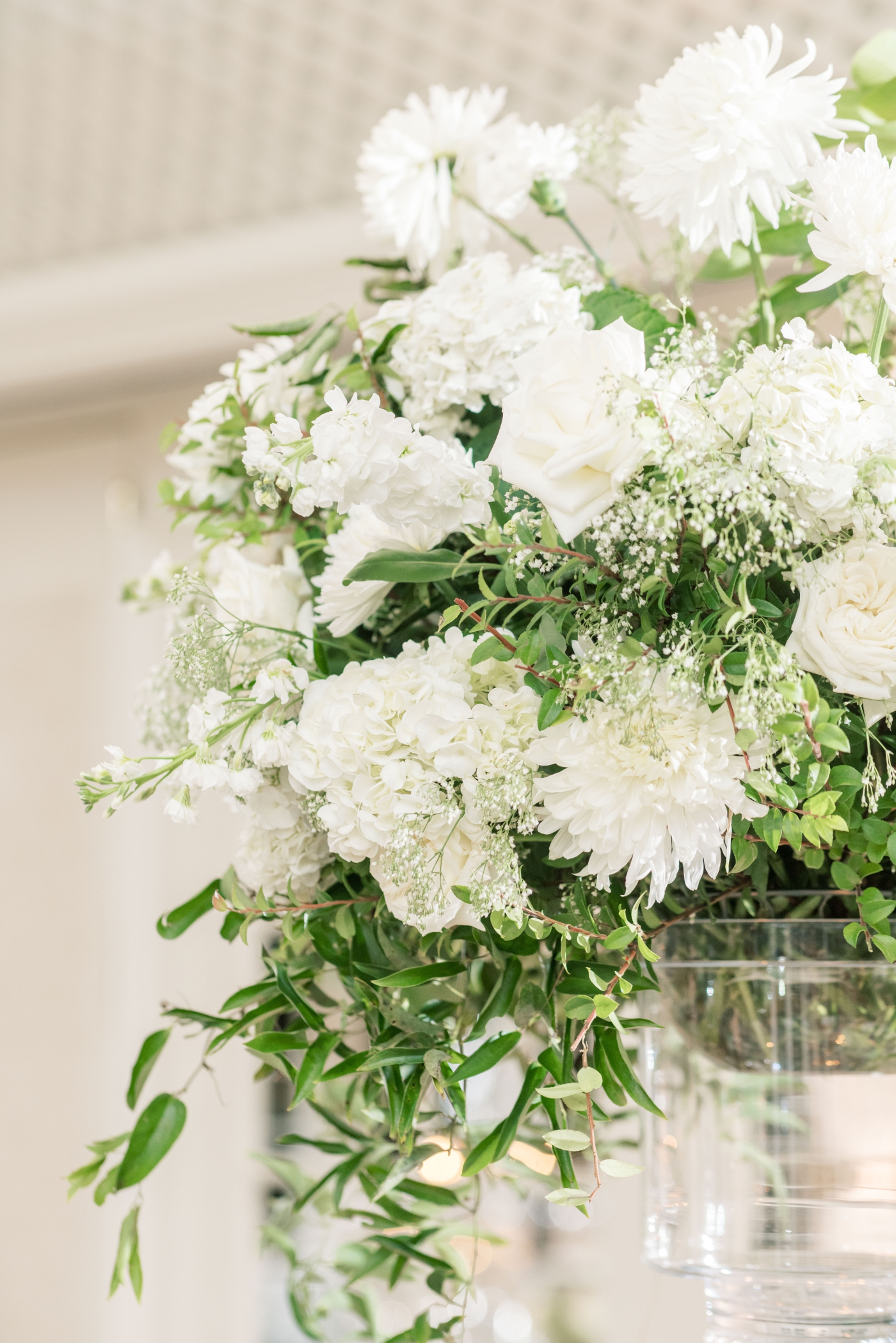 A close shot of a white flower arrangement with chrysanthemums and hanging greenery