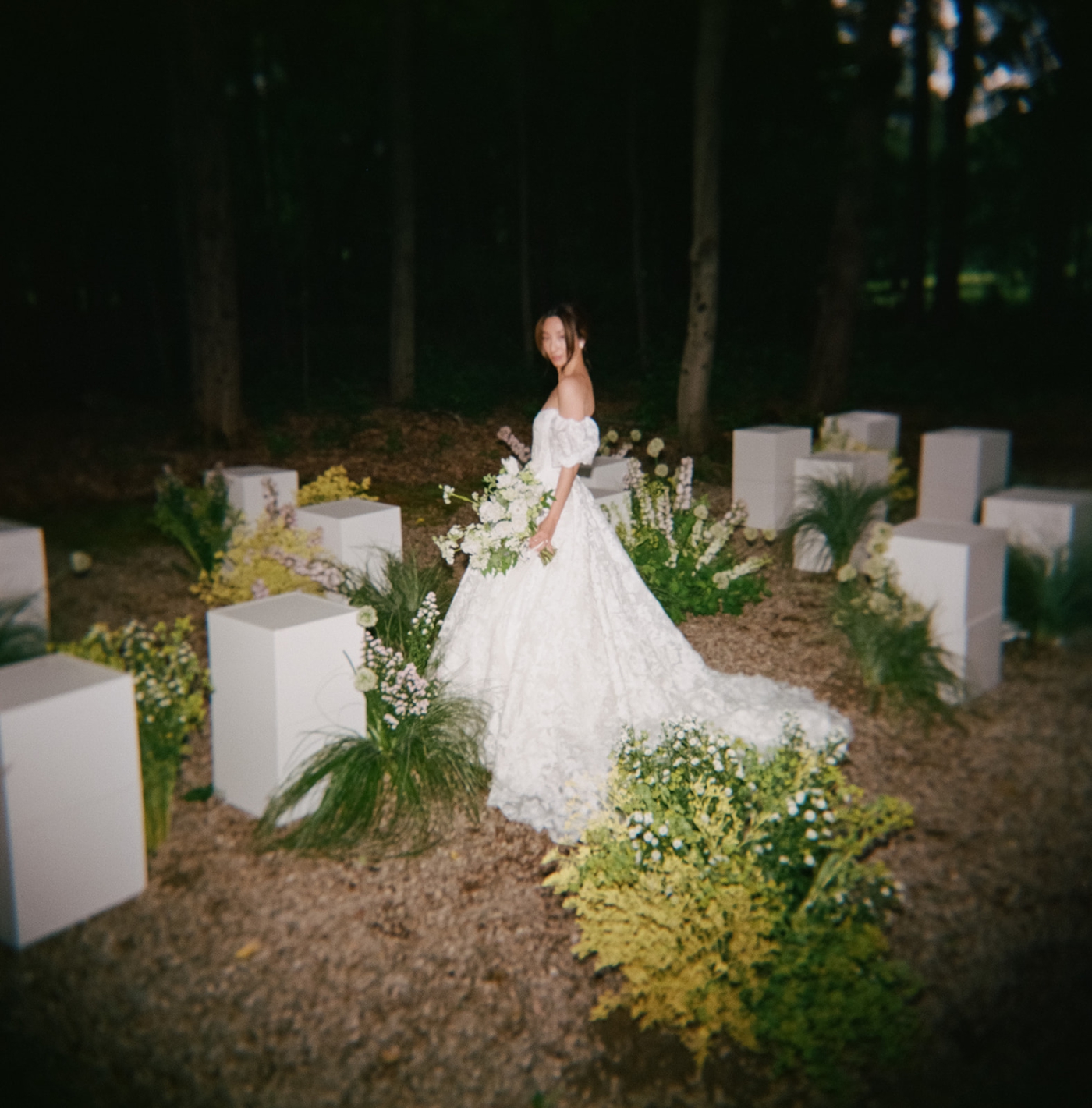 A film photo of a wedding ceremony at the Barn on Walnut Hill, with white pillars covered in flowers as the seats