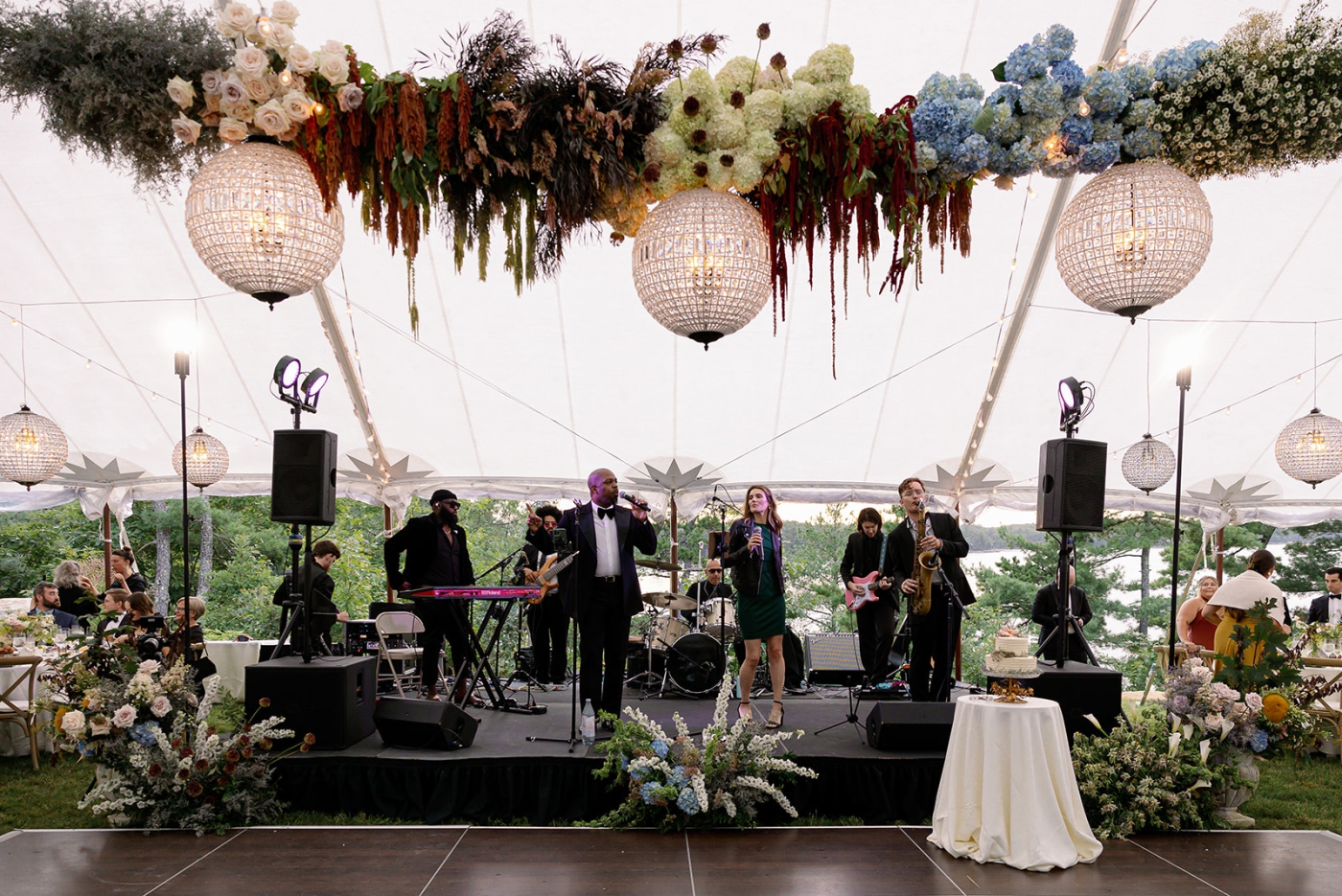A hanging floral arrangement above a dance floor with maroon and blue flowers and glass hanging lanterns