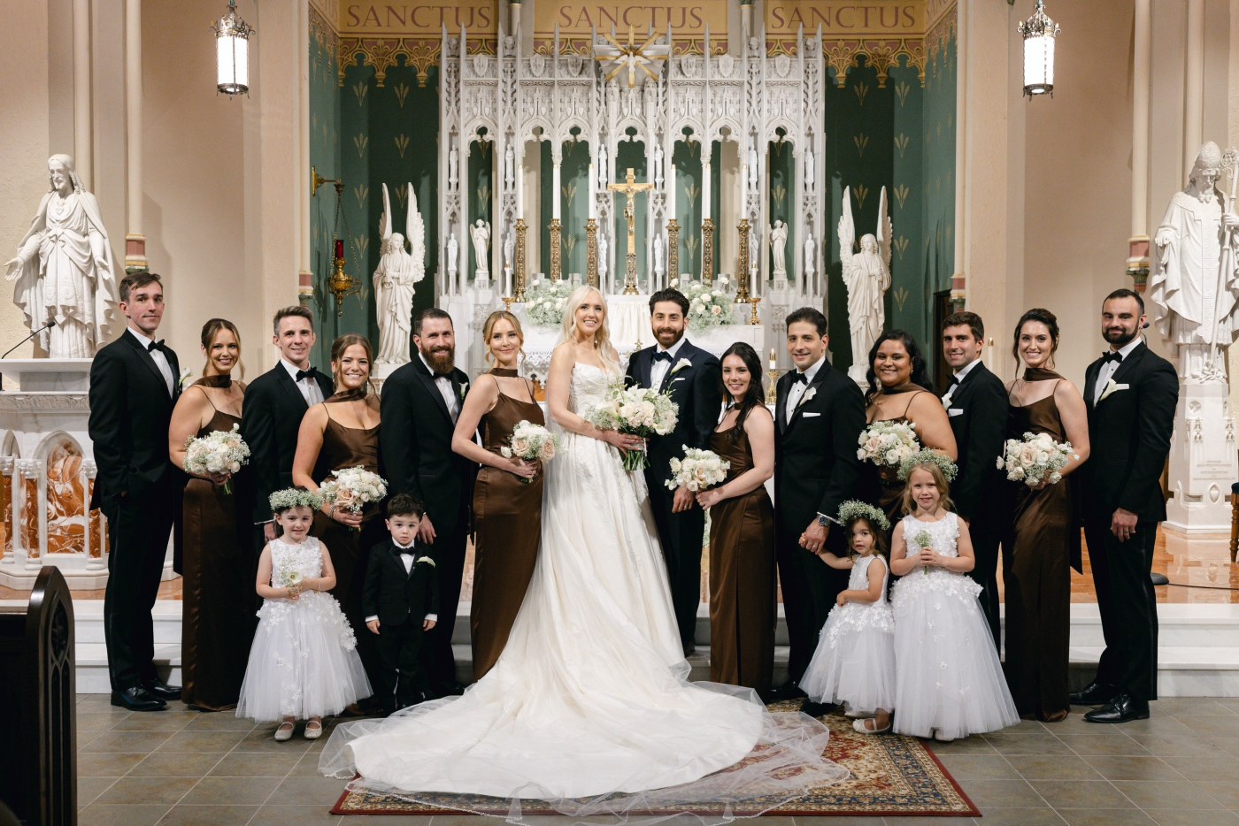 A bridal party in brown silk dresses holding white bouquets