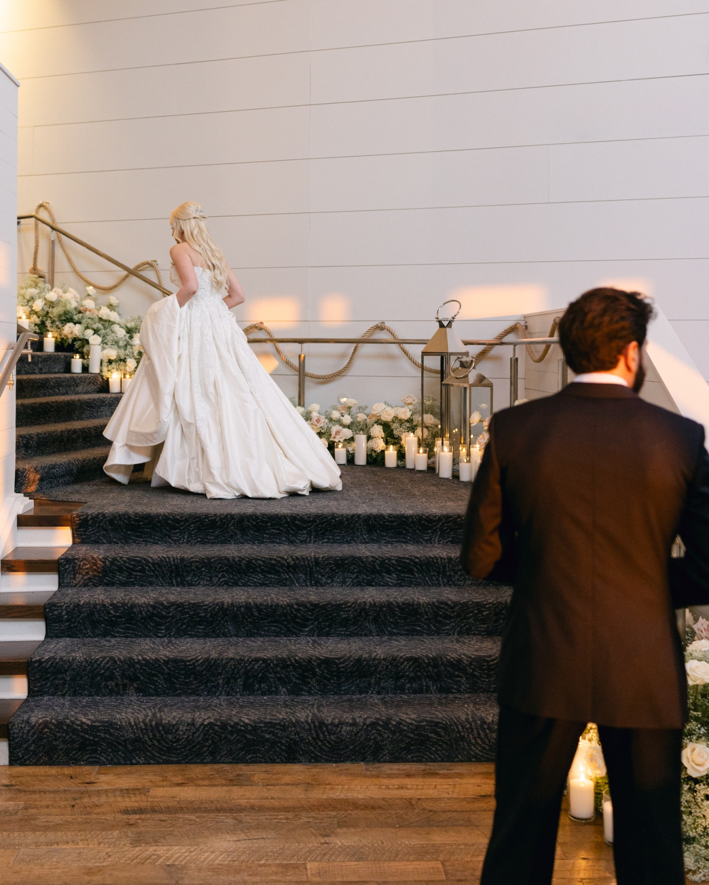 A bride ascending a staircase lined with white flowers