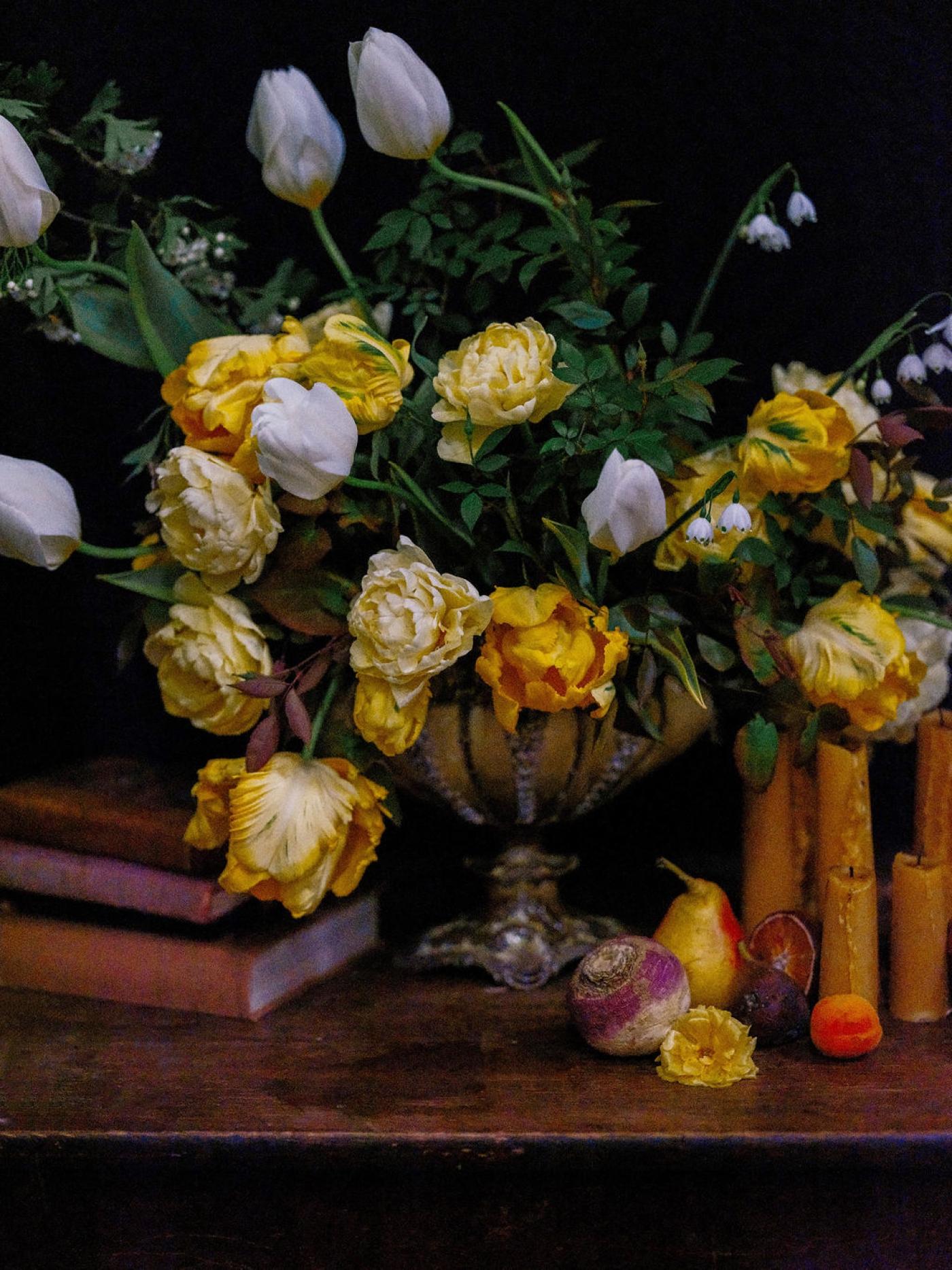 A bold yellow floral arrangement on a table with peaches