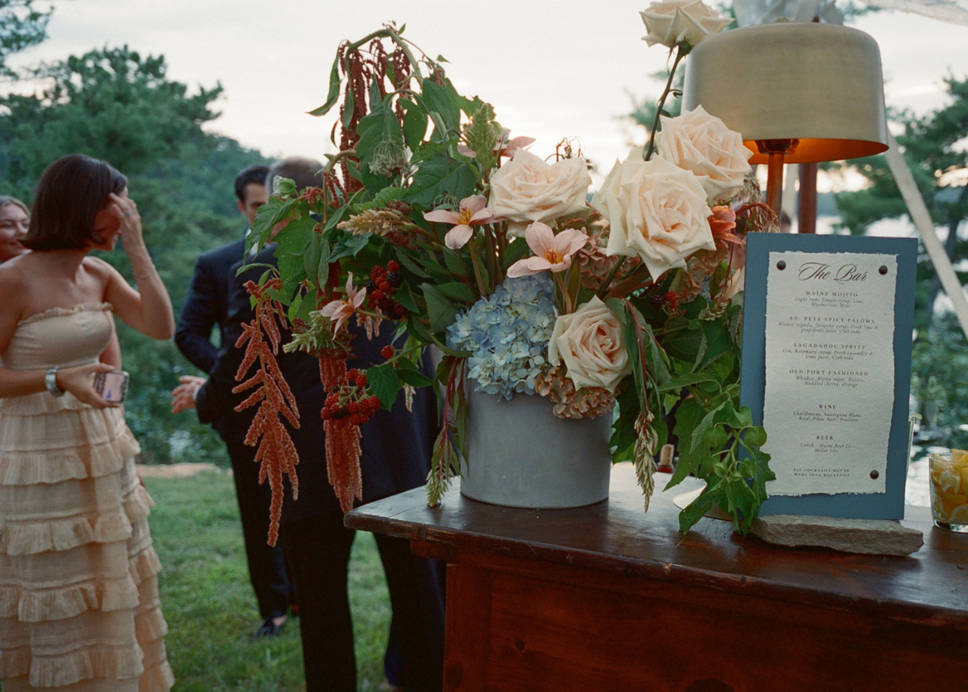 A floral design with maroon flowers mixed with pink roses and blue hydrangeas 