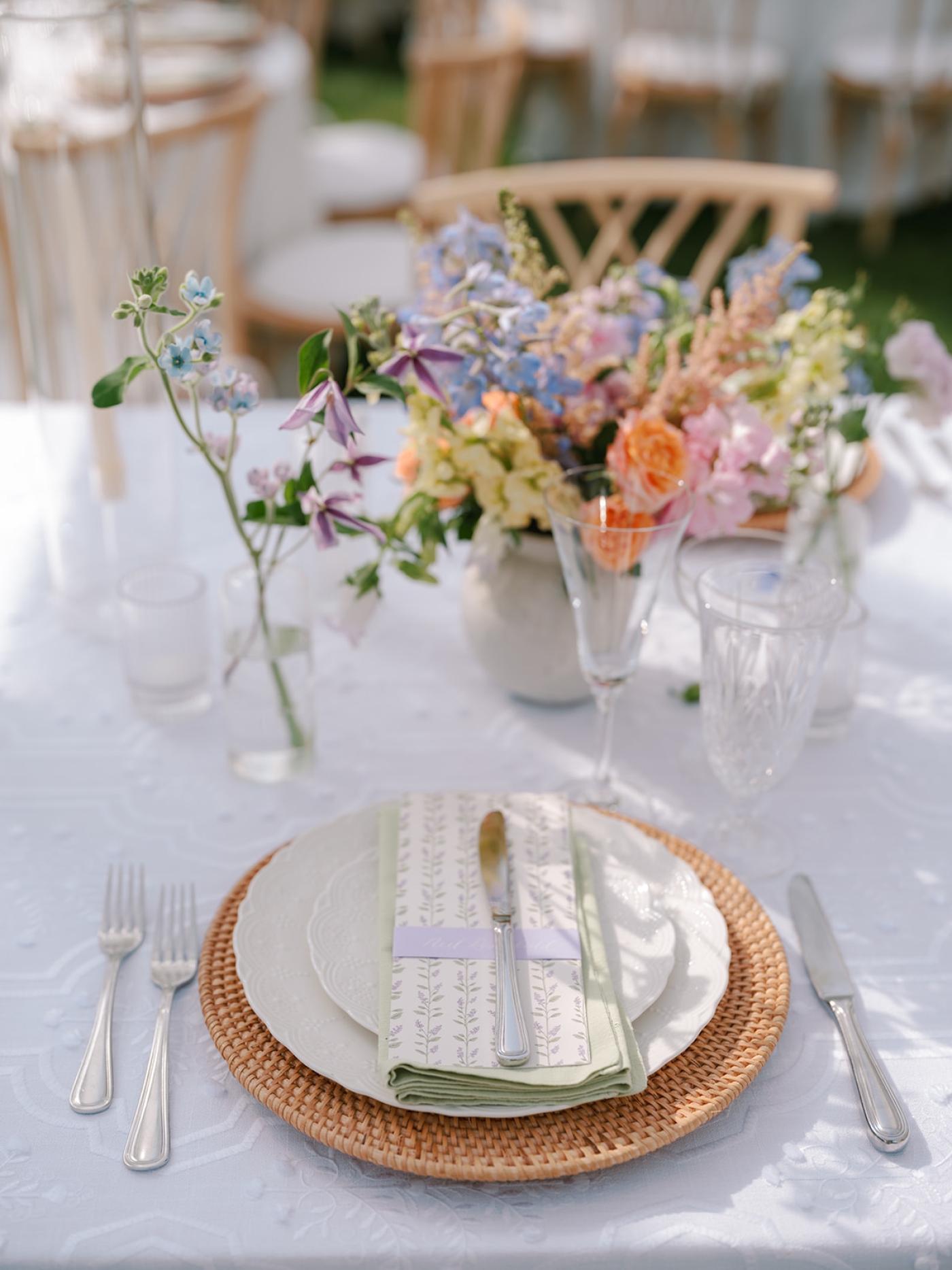 A place setting at a wedding with a small bud vase with pastel flowers