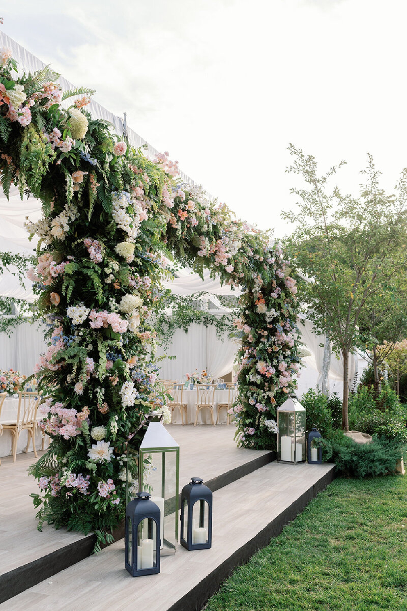 A large, colorful floral installation along the entrance to a cleartop tent
