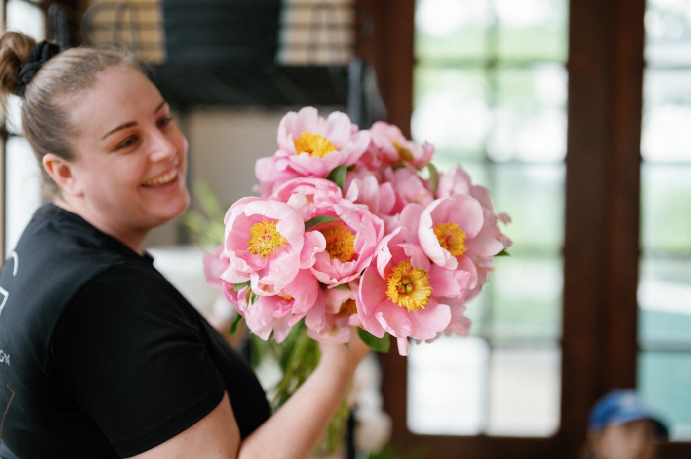 A florist holds a bouquet of pink peony wedding flowers 