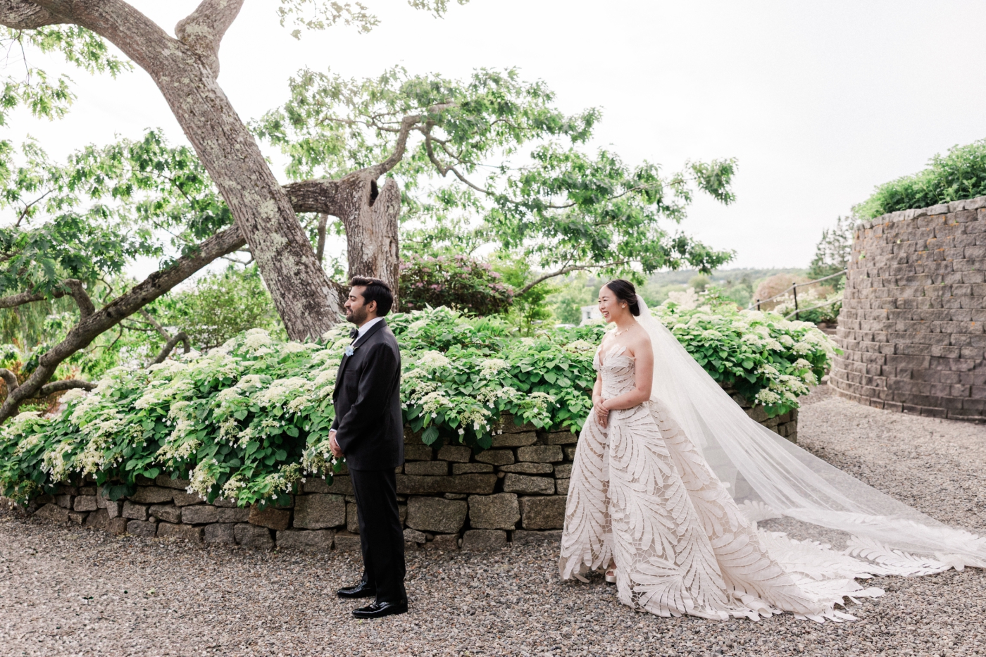 A bride stands behind the groom moments before a first look