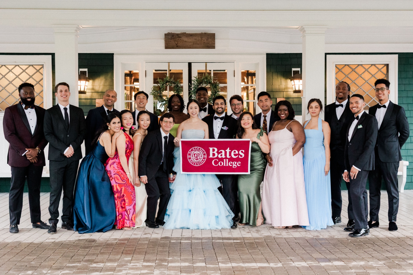 A large group photo of guests at a wedding holding a Bates College flag