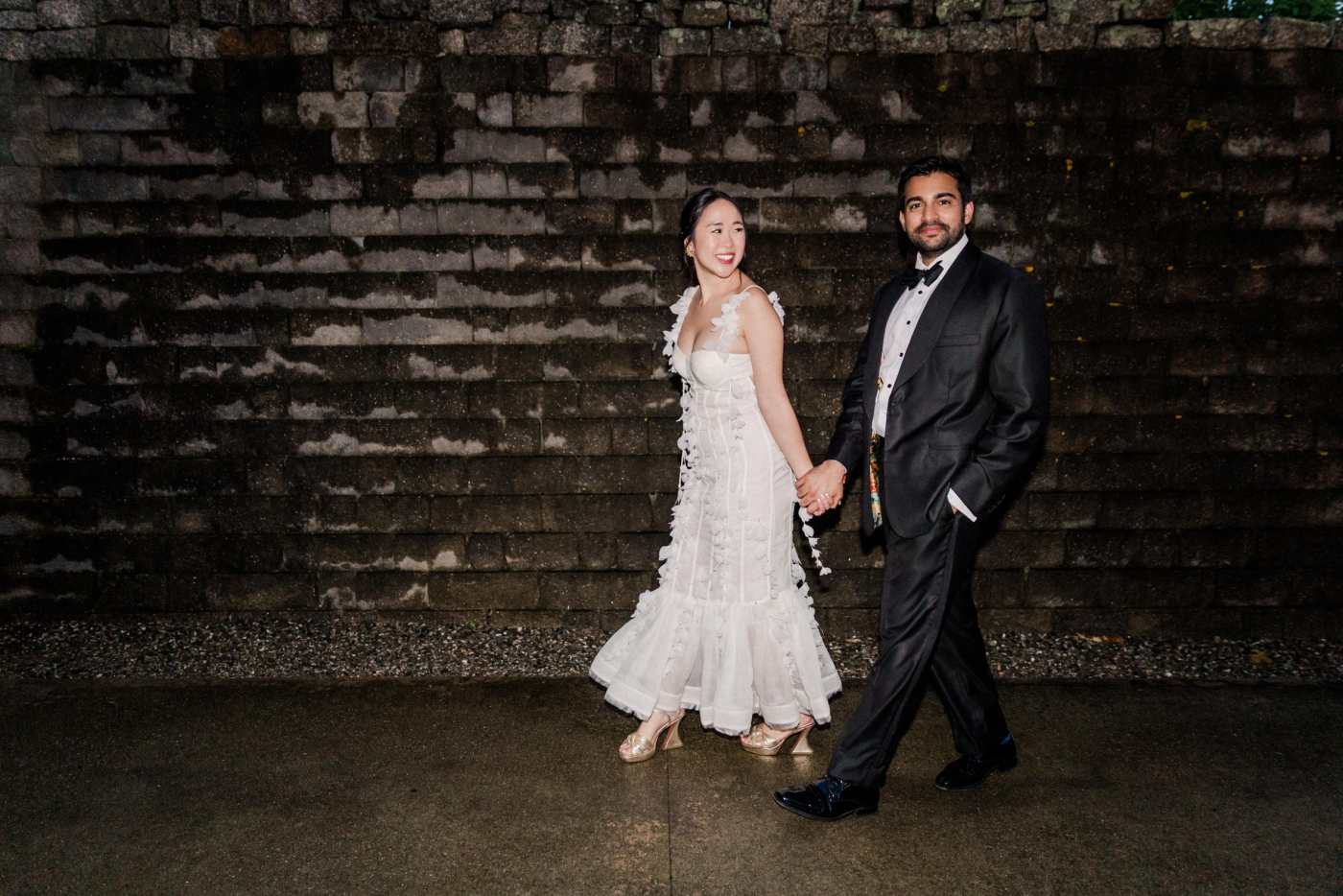 A bride and groom change into a second outfit and walk back to the reception tent during their wedding weekend celebration 